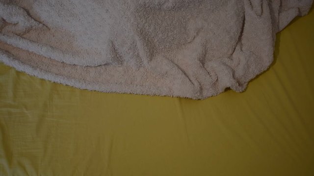 The sleeping woman in bed peeps out from under the covers and shows with her hand fuck