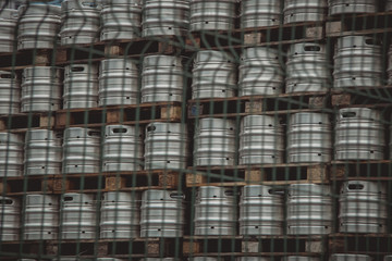Large amount of aluminium beer kegs stacked on each other with euro palettes and wrapped around...