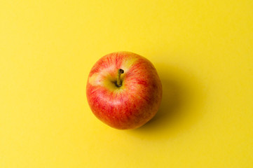 One red apple on a yellow background. The concept of ideas, weight loss and proper nutrition