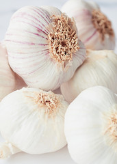 Pile of white garlic stacked on a light background.