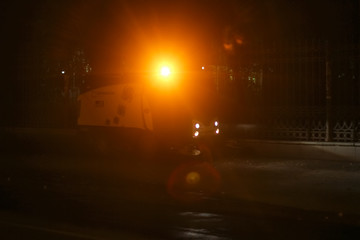 A small size sweeper cleans the street at night with a yellow flashing light on the roof |...