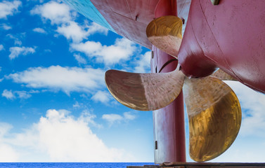 Propeller of a boat Navy close up, with rudder at stern ship after maintenance, repair already on blue sky background in shipyard.
