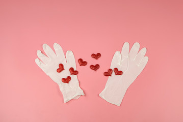 flat lay of red glitter hearts with medical gloves on pink background. concept medical care trying to save lives of people.Covid-19