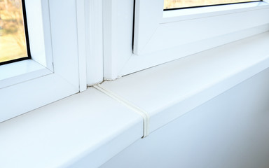 Modern white plastic window sill in the apartment. Low-quality joint of plastic window sills.Marriage during the decoration and installation of window sills.