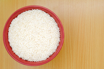 Rice in a red bowl on wooden background. Healthy breakfast concept.