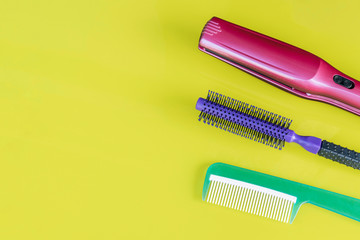 Beauty copy space on green background. Hairbrush and Hair straightener.