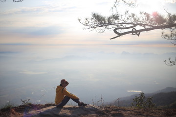 Woman sitting on a cliff waiting for sunrise in Phu Kradueng National Park, Loei, Thailand