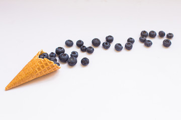 Blueberries and cone waffle on pink background. Be in shape with healthy snacks 