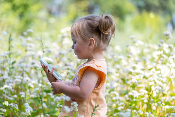 Little girl surrounded by white wildflowers exploring nature. The child decided to call