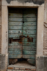 Green wooden door locked with a chain and a padlock golden iron