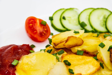 Homemade fried potatoes with fresh cucumbers, cherry tomatoes and sauces on the white plate. Delicious ukrainian fried potatoes with vegetables against background. Cooked tasty meal for lunch.