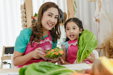 mother and daughter help each other to make salad in kitchen in the house