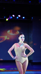 beautiful brunette posing in front of the camera on stage. girl ballroom dancer in the spotlight, sexy sensual girl in a dance leotard and necklace on a dark blue background dance poses