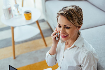 Happy female entrepreneur talking on the phone while working at home.