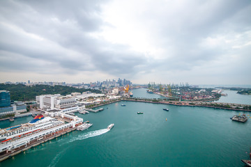 Fototapeta na wymiar Seaport in Singapore with a Large Cruise Liner, Boats and Cranes in the Background. Keppel Harbour or Keppel Channel