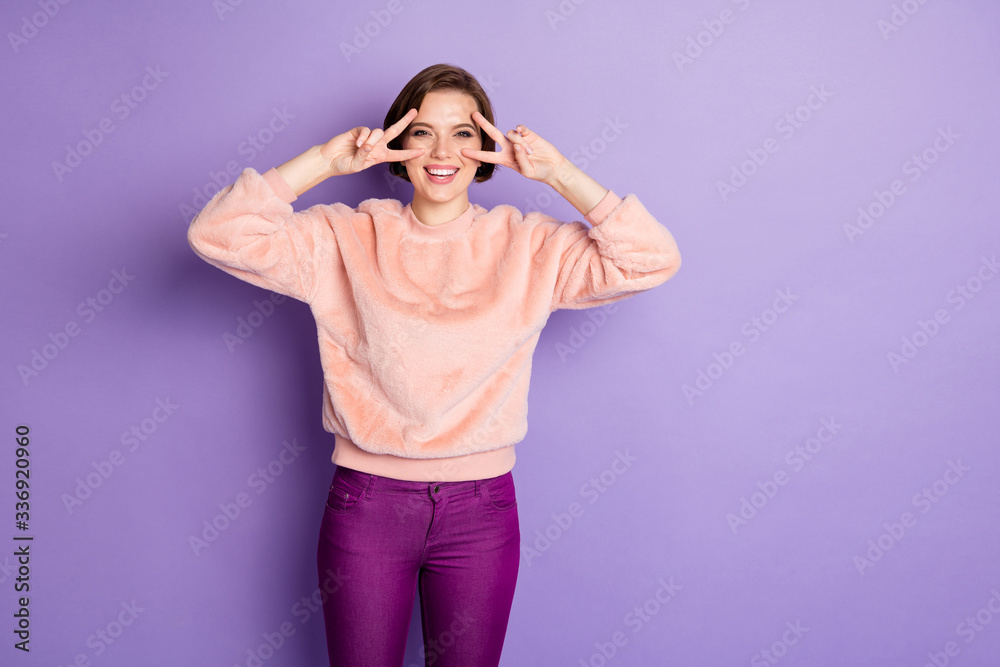 Sticker Portrait of cheerful positive funky youth girl make v-sign enjoy winter holidays feel satisfied emotions wear good looking clothes isolated over purple color background