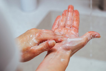 Close-up of woman using soap while washing hands in the bathroom.