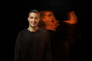 Smiling outside, shocked inside. The versatility of man - opened emotions and hidden feelings. Caucasian man on black background with different faces of condition. Double exposure. Mental health.