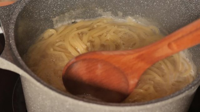 Spaghetti Al Dente Cooking On Steel Pan In Slow Motion Close Up.Pasta Boiled In Boiling Water In A Pan.Italian Cuisine.Close Up Spaghetti In Boiling Water.Linguine Cooked In A Pan.