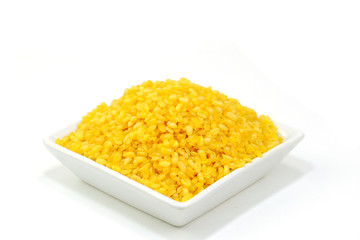 Organic split yellow mung beans (Yellow Moong Dal, Moong split washed, Lentisls) in a small plate ready to serve isolate on white background.