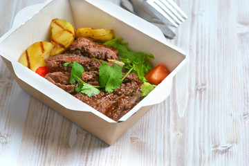 grilled steak and vegetables in a shipping container