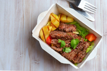 grilled steak and vegetables in a shipping container