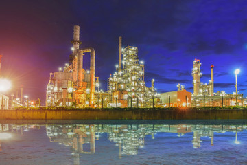 Oil refinery plant or power plant at dust with twilight and water reflection