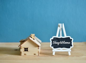 Social media awareness campaign and coronavirus prevention concept with word on small blackboard "STAY AT HOME" isolated on darkblue background.