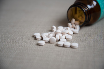 White pills, spilled from a jar. Pills close-up.