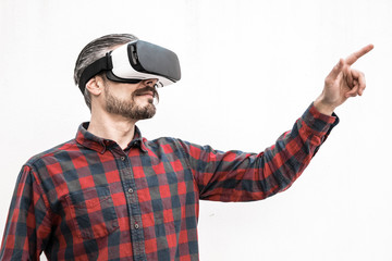 Focused man in VR headset moving hand. Serious bearded man in checkered shirt moving with hand and using VR headset on grey background. Technology concept