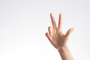 Kid hand showing and pointing up with fingers number three on white wall background
