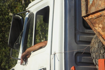 Hard work as a old truck driver, an oiled hand with a cigarette stuck out of the window