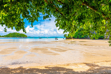 Panoramic view of east Railay beach, Krabi town, Thailand. View from the shadow of tree. Landscape with sand beach in foreground and huge limestone rocks in background. Summer day.