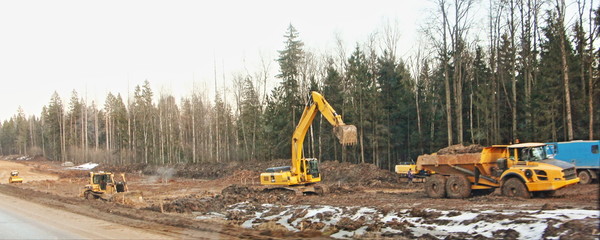 Heavy truck dump truck and crawler excavator on the construction site, equipment for moving soil in...