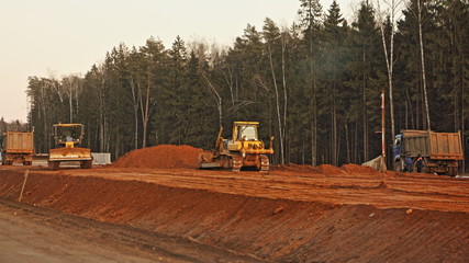 New highway road construction site, leveling the sand base with heavy machinery - dump trucks,...
