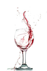 Splash of falling red wine in a round glass on a white background