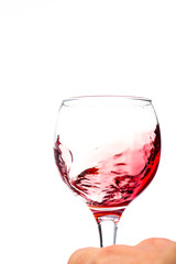 Splash of falling red wine in a round glass on a white background