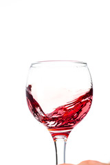 Splash of falling red wine in a round glass on a white background