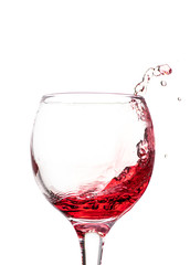 Splash of falling red wine in a round glass on a white background