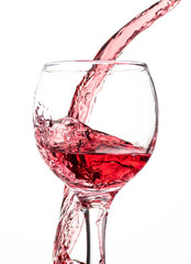 Splash of falling red wine in a round glass on a white background