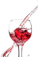 Splash of falling red wine in a round glass on a white background