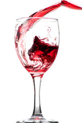 Splash of falling red wine in a round glass on a white background