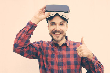 Naklejka premium Man in VR headset showing thumb up. Happy handsome man using virtual reality headset and smiling at camera. Technology concept