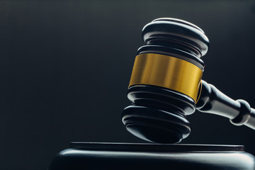 Judge's gavel with gold metal on a black table. Concept of law