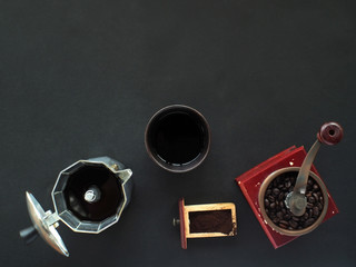 Fresh coffee from Moka pot and coffee grinder In the black background. coffee at home
