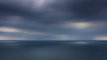 Looking out to the ocean horizon from St Alban's Head as the sun tried to break through the dark clouds, Dorset, UK