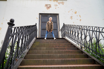 Blonde funny pretty girl on stairs with railing in Central part of old city. Portrait of girl on street