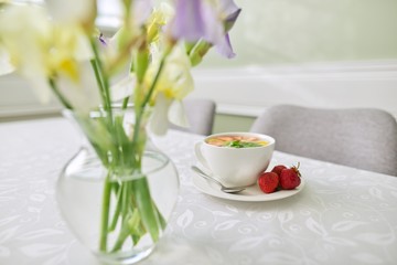 Obraz na płótnie Canvas Strawberry tea on table, with vase of irises flowers