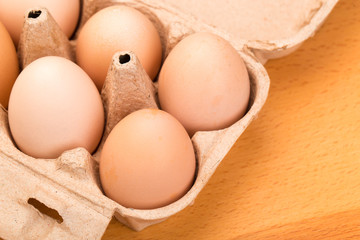 brown chicken eggs in an open cardboard box with eggs on a wooden table. Natural healthy food.