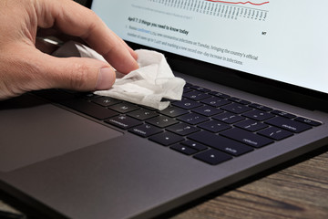 Hand of a Man Wipes a Laptop Keyboard with a Damp Cloth